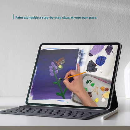 A tablet in a black protective case with a keyboard cover stands on a white surface against a light gray wall. The screen shows a hand holding a paintbrush and painting alongside a digital paint palette.